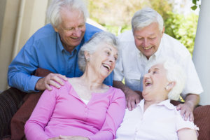 Group of senior friends sitting on garden seat laughing